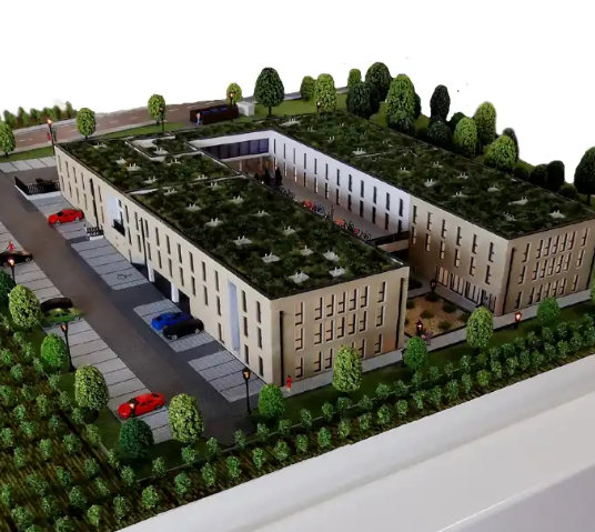 A high-impact exhibition scene for Design Week Vienna featuring a custom illuminated and animated scale model by ARI Model that visualizes a mixed-use innovation block, EV charging plazas, autonomous shuttle routes, human-scale public spaces, and mat